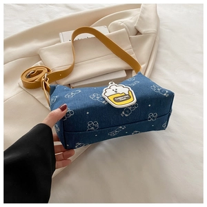 Detailed view of dark blue denim shoulder bag with bear print and yellow leather strap