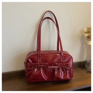 Detail view of burgundy leather shoulder bag with bow-decorated pockets and glossy finish