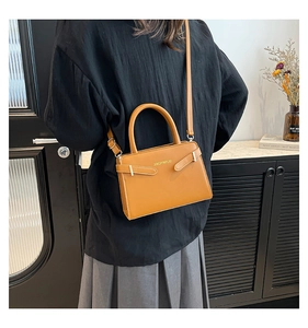 Gros plan du sac bandoulière marron avec boucle métallique et détail de poignée ronde