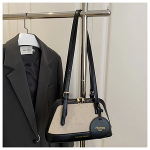 Detail of canvas and black leather shoulder bag with gold hardware and logo tag