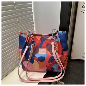 Detail of colorful geometric pattern tote bag with pink leather straps and silver hardware