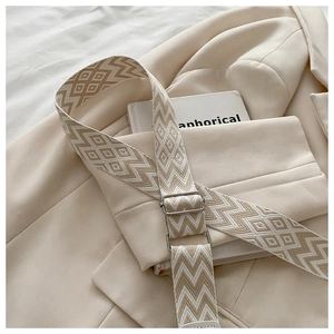 Detail of wide woven strap with geometric diamond pattern and silver metal buckle