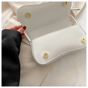 Detailed view of white leather crossbody bag with golden magnetic snap button closures