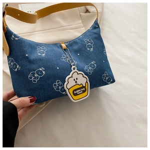 Detailed view of denim shoulder bag with white bear prints and yellow leather strap