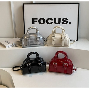 Close-up of four colors of glossy leather boston bags with buckle details and dual handles