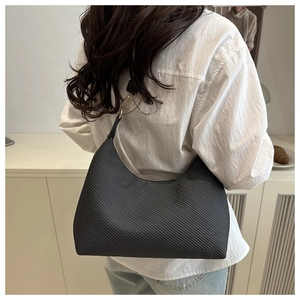Detailed texture view of black crescent shoulder bag with golden zipper on a model's shoulder
