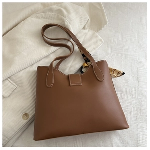 Detail of a brown leather bucket bag with contrast stitching and floral silk scarf detail
