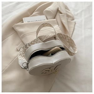 Detail of cream heart crossbody bag with SM logo and textured wide fabric strap