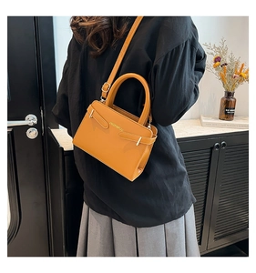 Vue latérale d'un sac à bandoulière en cuir jaune gingembre avec finitions dorées chic