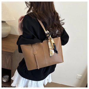 Brown tote bag with contrast stitching and silk scarf detail shown on shoulder