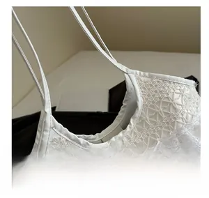 Close-up of intricate white lace embroidery and delicate straps on a summer tote bag