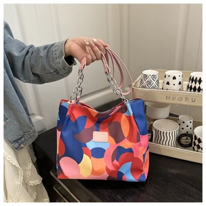 Detail of color-block tote bag with metal chain handle and JINGPIN fashion label