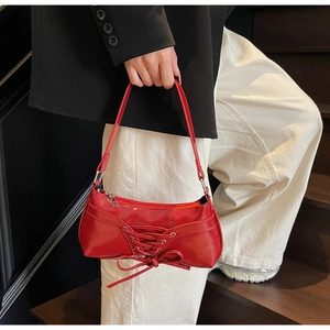 Macro view of bright red PU leather underarm bag featuring decorative lacing and bow