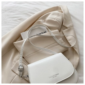 Détail du sac de selle en cuir blanc crème avec texte Fashion Trend Est 1996 gravé
