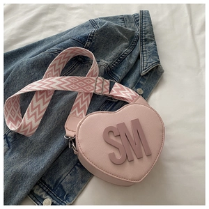 Pink heart-shaped crossbody bag with SM logo and geometric pattern wide woven strap