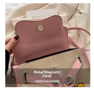 Detail of color-block handbag showing shiny silver magnetic clasp and cartoon bear logo