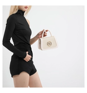 Close-up of the cream leather box bag with woven panel and golden M-shaped metal clasp
