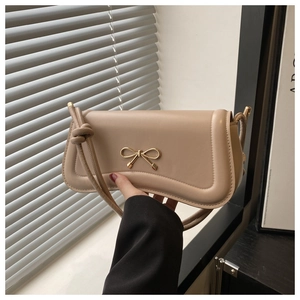 Detail of beige leather crossbody bag with golden bow and elegant knot handle