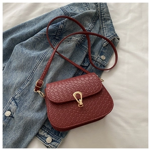 Detail of burgundy woven square bag with golden buckle on denim jacket