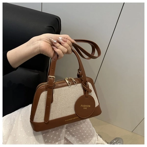 Detail of vintage canvas and brown leather patchwork bag with gold zipper and round tag