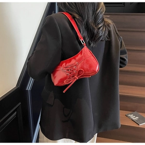 Detail view of bright red glossy PU leather shoulder bag with chic bow and lace-up design