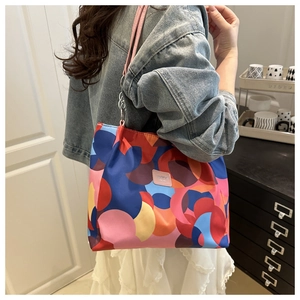 Detail of colorful geometric tote bag featuring pink leather strap and metal chain