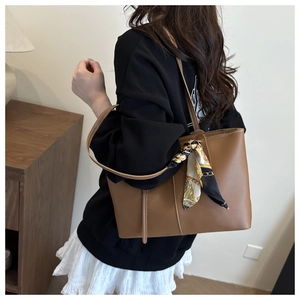 Brown leather tote bag detail with decorative silk scarf and large shoulder strap