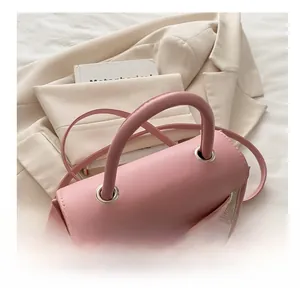 Detail of pink and beige patchwork handbag with thick handle and embroidery accents