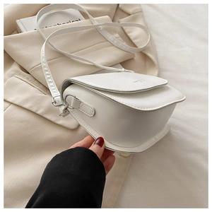 Gros plan sur un sac selle en cuir blanc avec rabat et bandoulière réglable