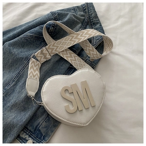 Detail of white heart-shaped PU leather bag with SM initials and patterned wide strap