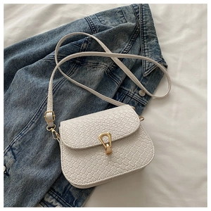 Detail of white woven texture shoulder bag with gold horsebit buckle on denim fabric