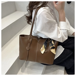 Detail of vintage brown tote bag with V-shaped cut and silk scarf on a model
