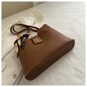 Detailed view of a brown shoulder bag with gold metal buckle and elegant silk scarf charm