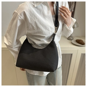 Detail of minimalist black crossbody bag with diagonal ribbed texture and gold hardware