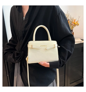 Détail du sac en cuir crème avec boucle en métal doré et bandoulière assortie élégante