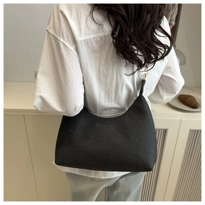 Détail du sac hobo noir texturé avec finitions dorées porté à l'épaule chic