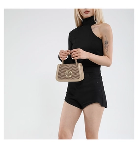 Detail of a chic beige herringbone mini handbag with a gold logo and structured handle