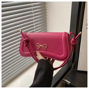 Detail of rose pink handbag featuring a gold bow buckle and knotted shoulder strap design