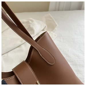 Close-up of brown bucket bag showing white contrast stitching and fine leather texture