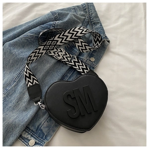 Detail view of heart-shaped crossbody bag with SM logo and geometric jacquard strap