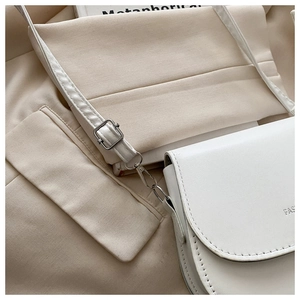Vue macro d'un sac selle blanc montrant les boucles en argent et les détails de couture