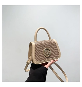 Detail of two-tone crossbody box bag featuring woven texture and gold metal M logo