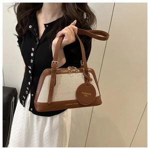 Close-up of a vintage canvas and brown leather handbag with gold metal hardware details