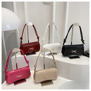 Group view of leather crossbody bags in five colors with bow detail and curved base