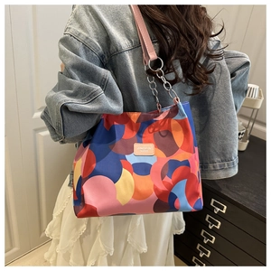 Detail of colorful geometric print canvas tote bag with pink leather strap and chain