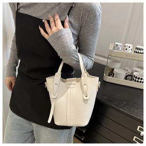 Detail of white lychee leather bucket bag with wide handle and silver metal hardware