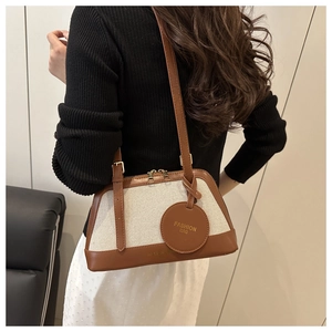 Detail of canvas and brown leather shell bag with gold fashion tag shown on model