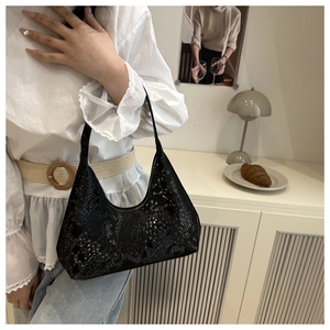 Detail of black python texture hobo bag worn by a model in an elegant interior setting