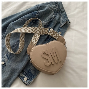 Detail of khaki heart-shaped crossbody bag with SM logo and decorative zigzag wide strap