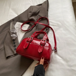 Retro red waxed PU leather bowling bag with silver buckle and crossbody strap on blazer